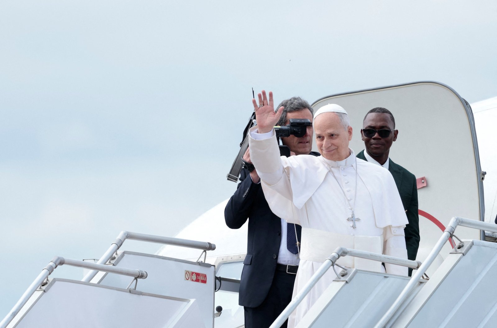 Pope Leo waves as he boards the papal plane