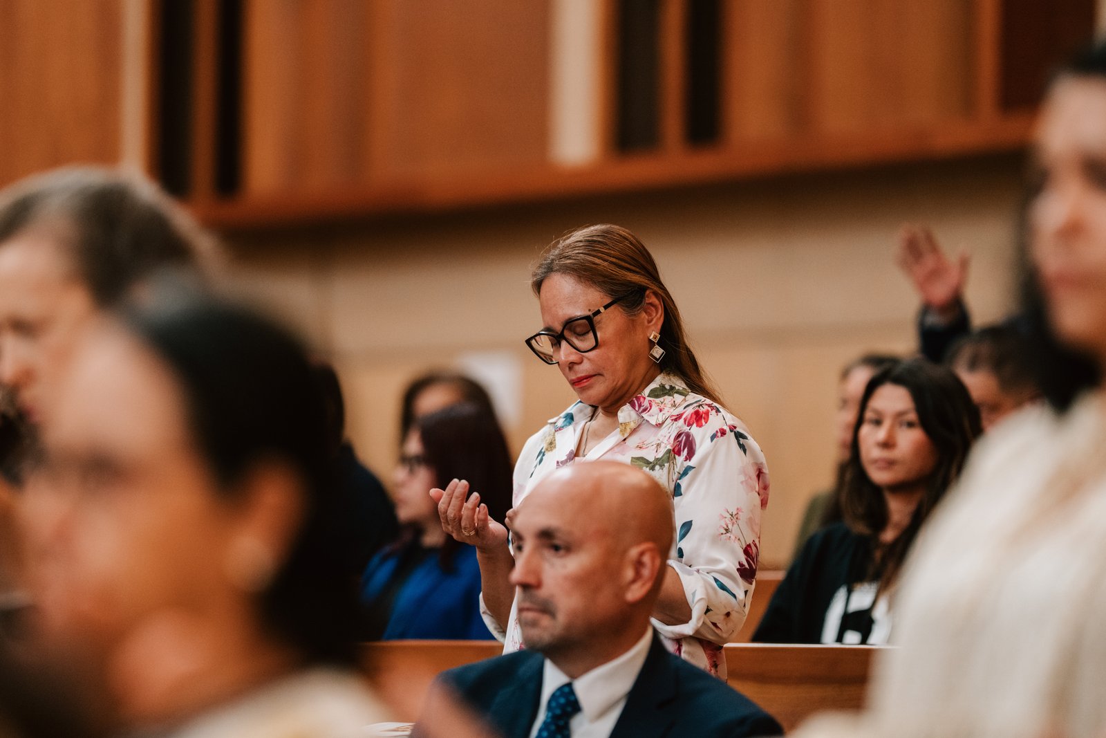 People attending the Mass have their arms outstretched in receiving a blessing.