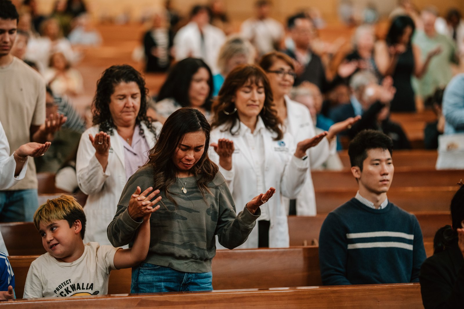 People attending the Mass have their arms outstretched in prayer.