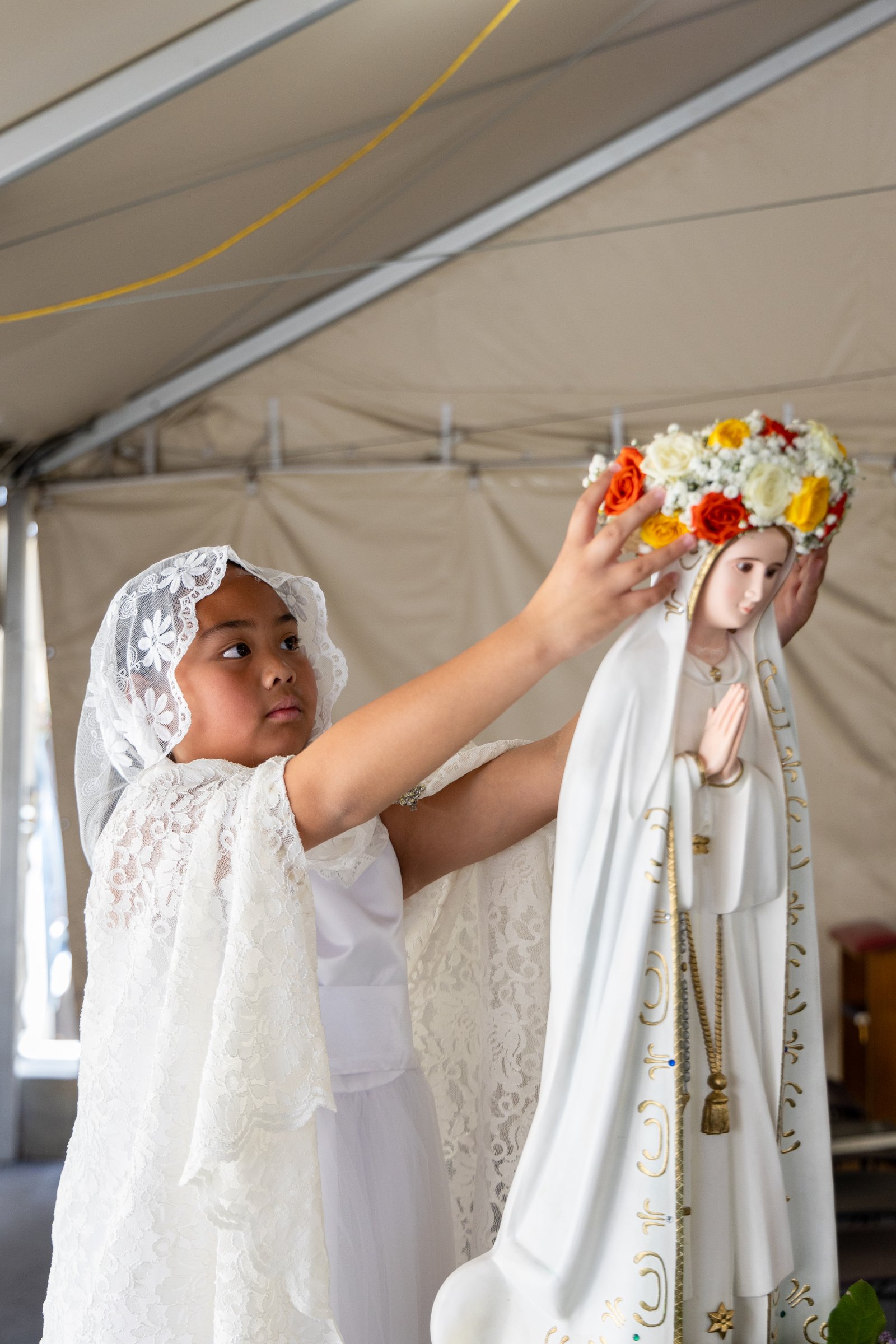 A young girl places the crown of flowers on Mary's statue during a May Crowning event on May 12 at St. Vitus Church in San Fernando. (Daniel Parra)