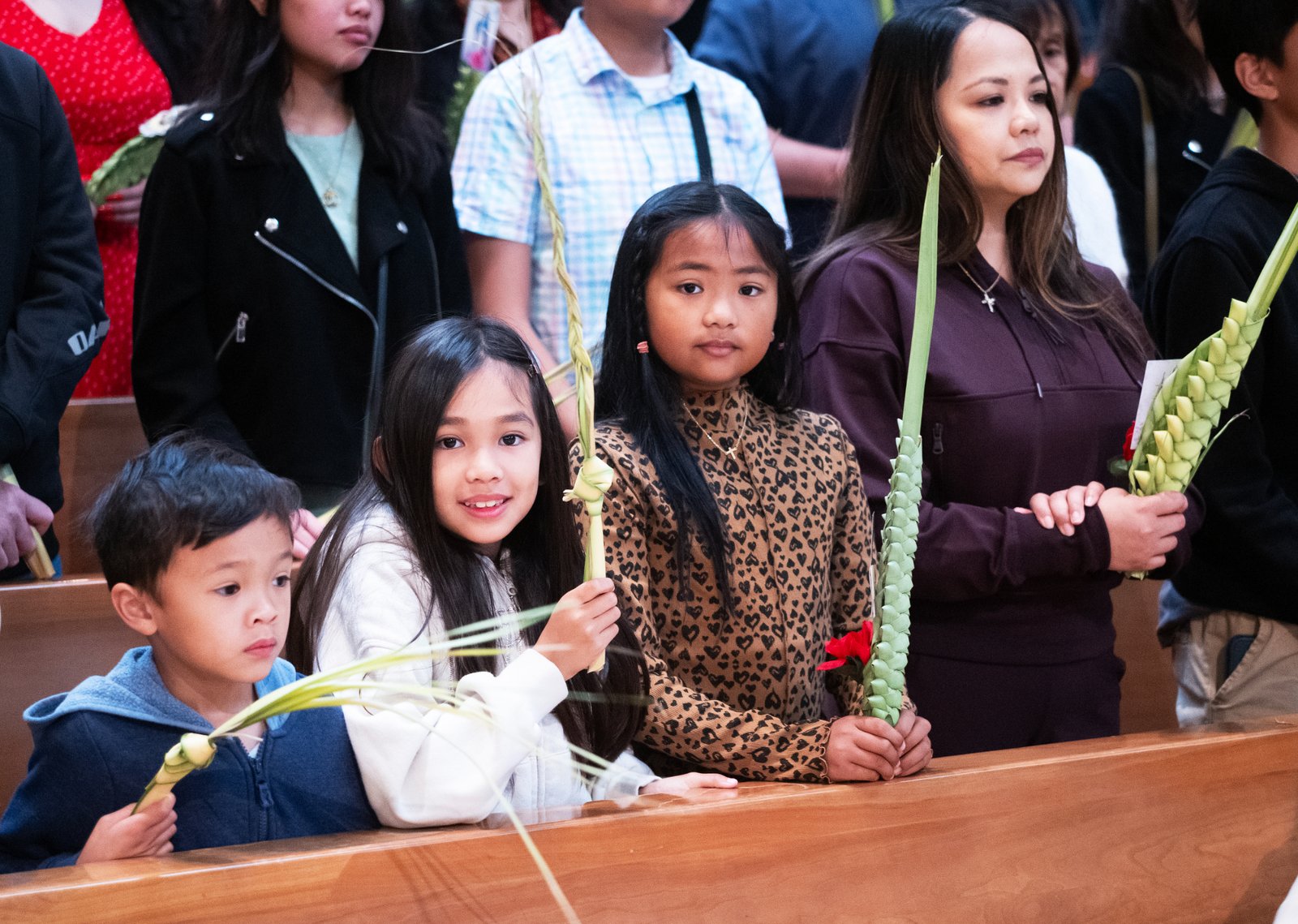 A family smiles as they clutch their palms at the Cathedral of Our Lady of the Angels during the Palm Sunday Mass on April 13. (Victor Alemán)