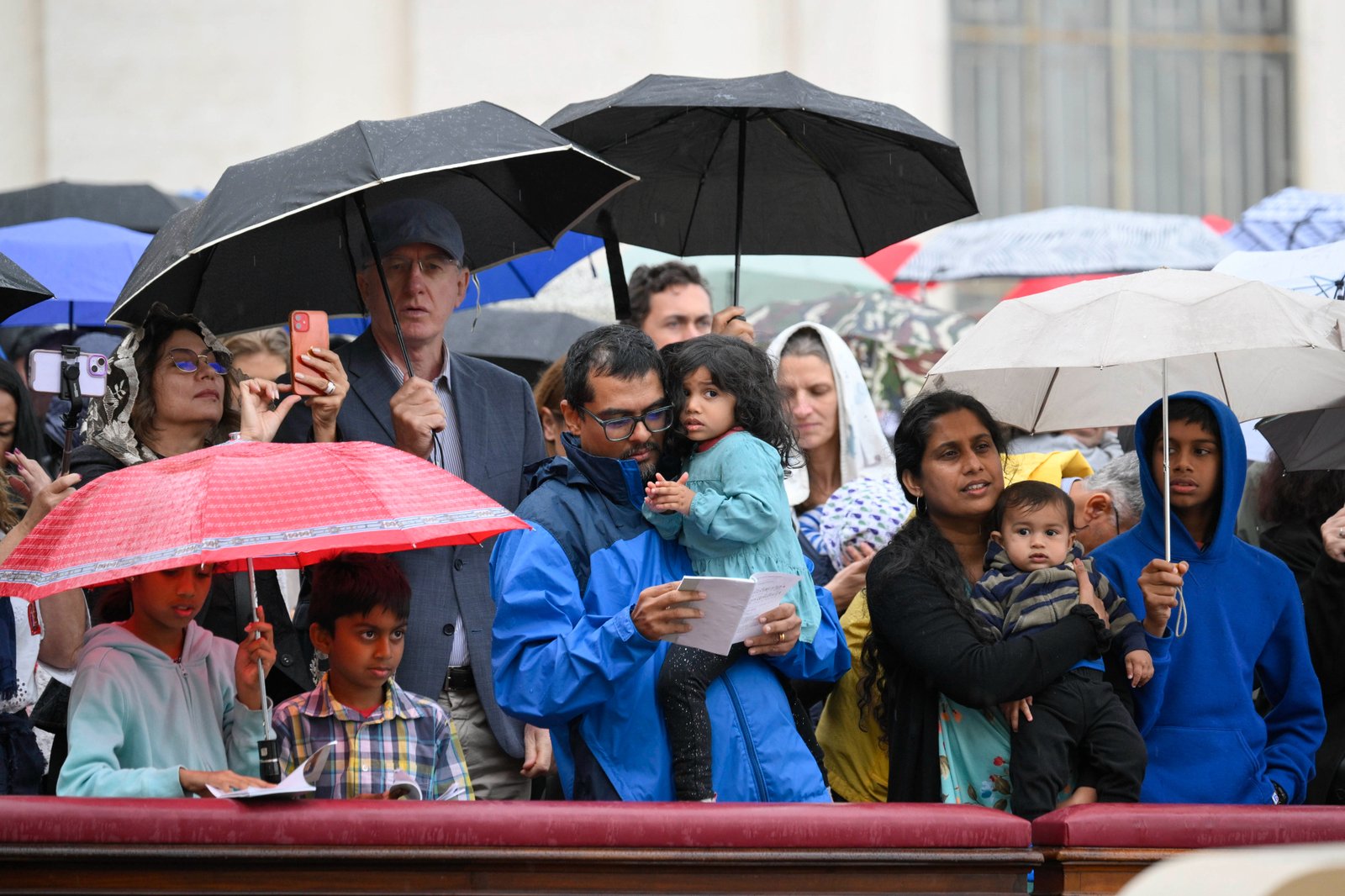 Pilgrims huddle under umbrellas as intermittent rain falls during Pope Leo XIV's Mass for the Jubilee of Migrants and the Jubilee of the Missions in St. Peter’s Square at the Vatican Oct. 5, 2025. (CNS photo/Vatican Media)