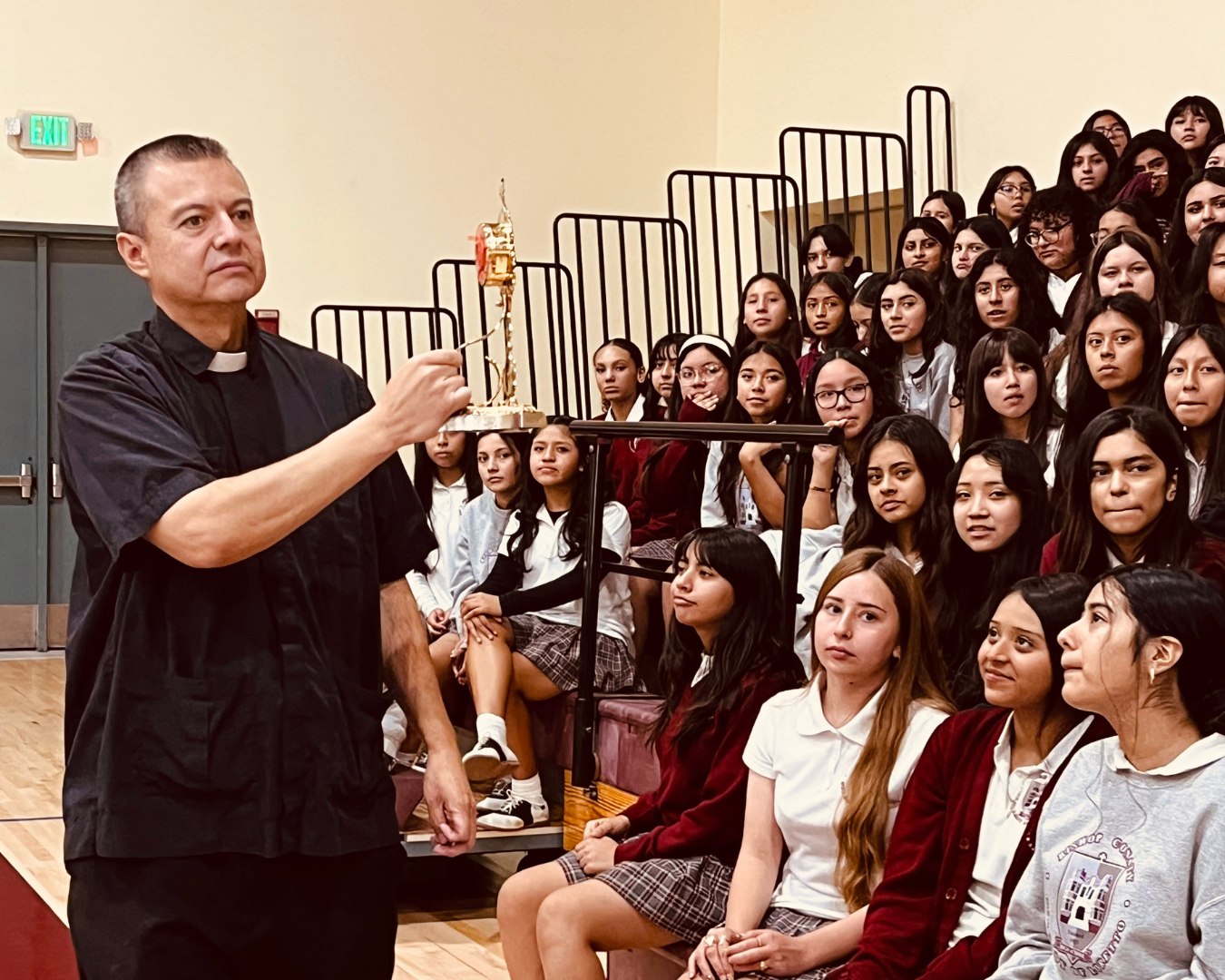 Father Mario Torres, pastor of St. Thomas the Apostle Church, shows the relic of St. Carlo Acutis to students at Bishop Conaty - Our Lady of Loretto High School on Oct. 21 during a tour of the saint's relics. (Bishop Conaty - Our Lady of Loretto High School)