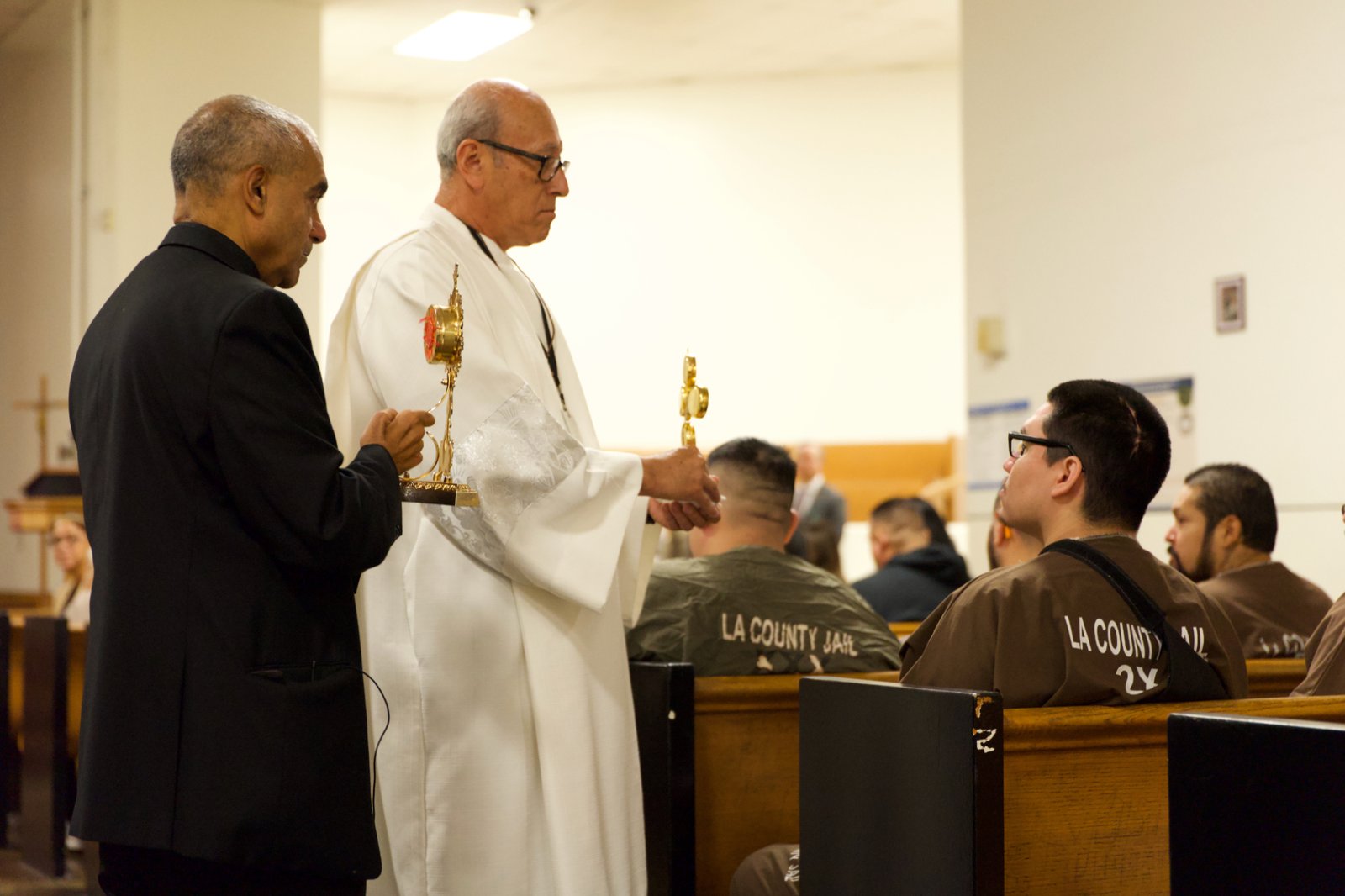 Msgr. Anthony Figueiredo, left, a priest in Assisi, Italy, speaks to inmates at LA Men’s Central Jail about the life of St. Carlo Acutis before Mass Oct. 20. At his right is Deacon Fermin Lopez. (Reese Cuevas)
