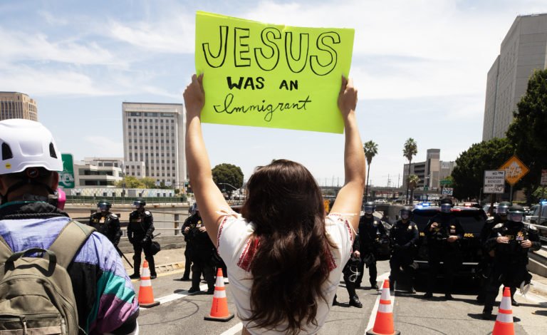 Una mujer sostiene un cartel frente a una salida cerrada de la autopista 101 durante una manifestación “No Kings” en el centro de Los Ángeles el 14 de junio. (Víctor Alemán)
