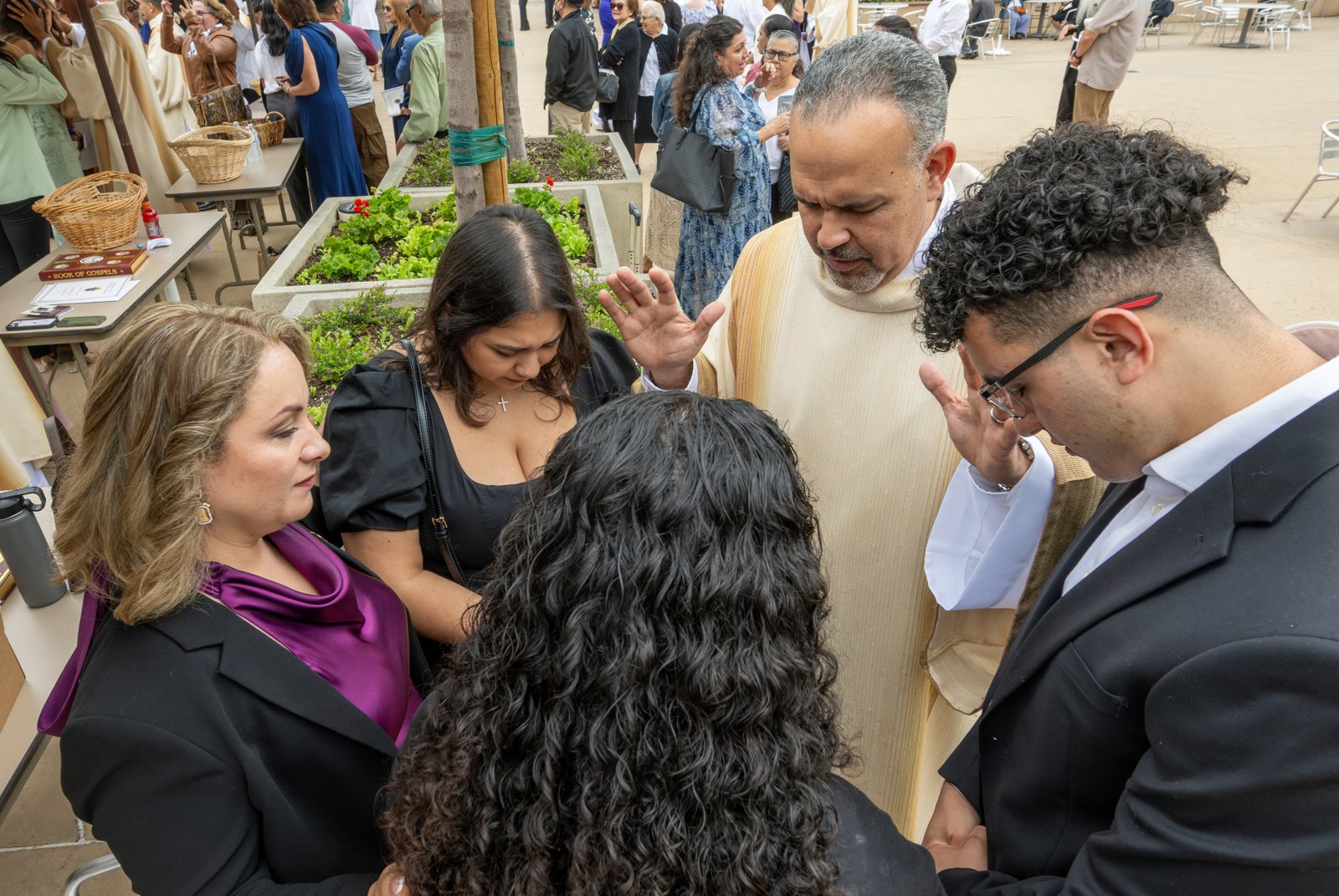El diácono Ariel Santiago ofrece su primera bendición a su esposa Amalia, a su hija mayor Daisy Sánchez, a su hijo Ariel Jr., y a su hija menor Narelly, en la plaza exterior de la catedral tras la Misa de ordenación. (John McCoy)