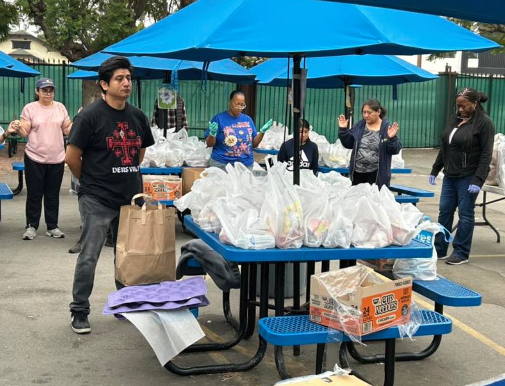 Miembros del Ministerio SHARE de la Iglesia Santa Águeda en Los Ángeles oran durante una distribución de alimentos el 12 de julio para familias necesitadas. (Veronica Reyes)
