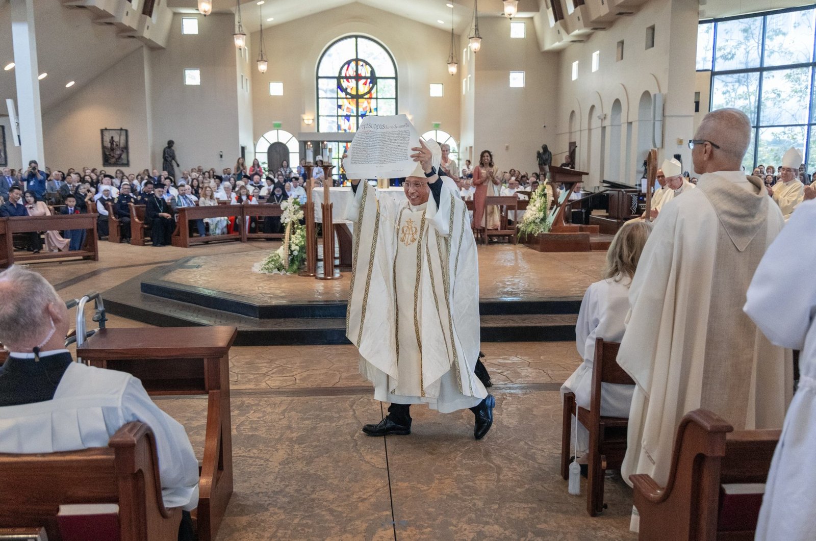 El obispo Michael M. Pham muestra la bula papal que lo designa séptimo obispo de la Diócesis de San Diego a la comunidad reunida en la iglesia St. Therese of Carmel en San Diego, California, para su instalación el 17 de julio de 2025. (OSV News/Charlie Neuman, The Southern Cross)