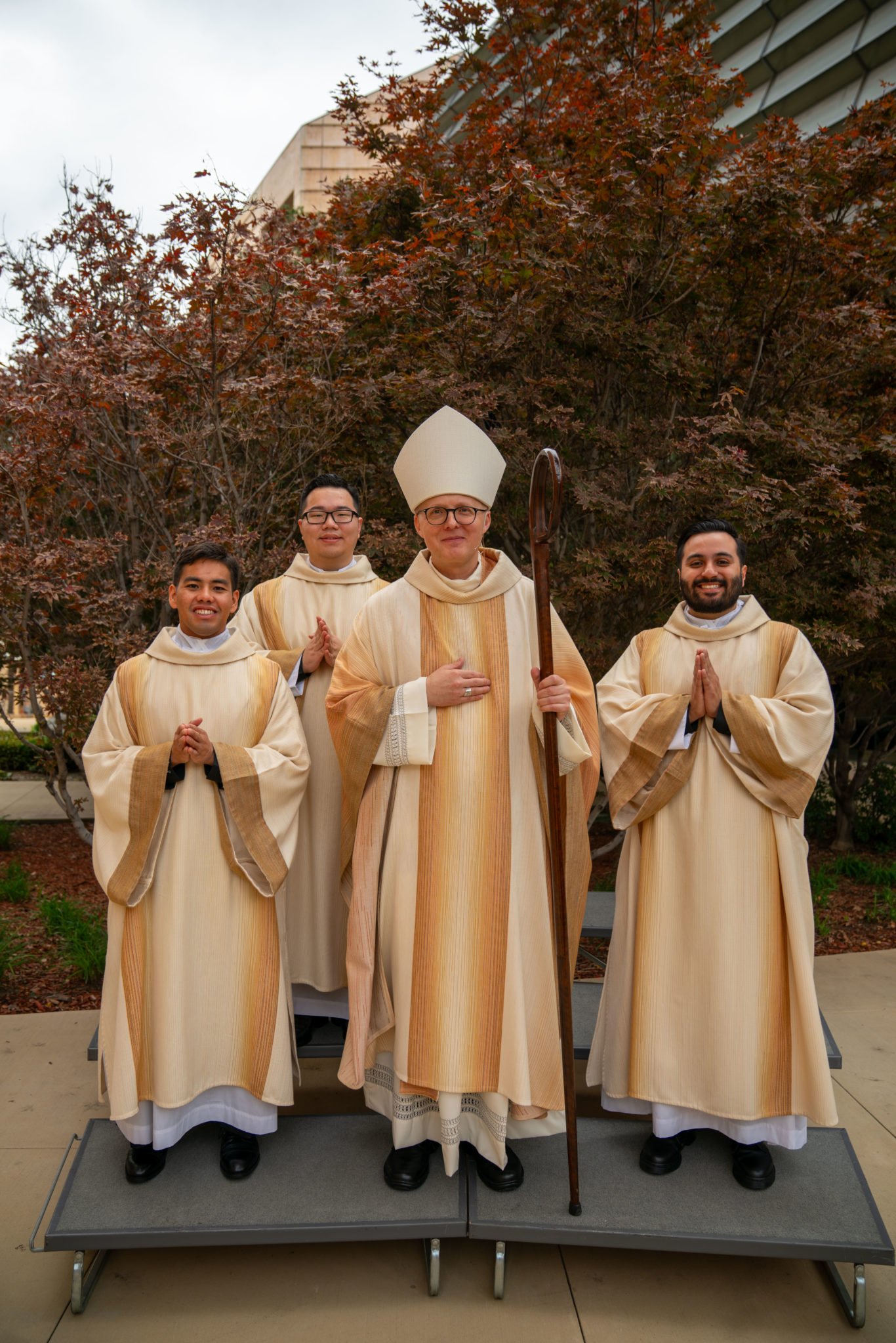 El obispo auxiliar Slawomir Szkredka posa con los nuevos diáconos Jerick Alenton, Shengda Zhu y David Zamora tras la Misa de ordenación. (John Rueda)