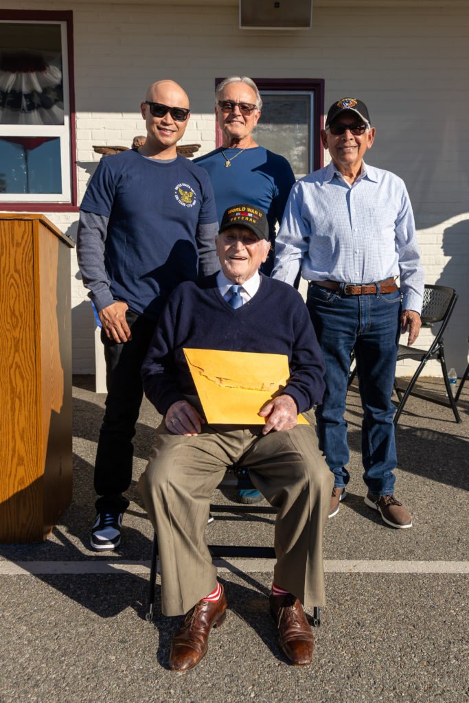 Joe “Peppy” Sciarra, un veterano de la Segunda Guerra Mundial de 100 años, posa con Mervin Vergara, arriba a la izquierda, un padre de familia de la escuela que actualmente sirve en la Marina de EE.UU.; el hijo de Sciarra, Joe, arriba al centro; y Aurelio Anaya, un veterano de la Guerra de Vietnam, arriba a la derecha, durante un evento por el Día de los Veteranos en Holy Angels School en Arcadia el 10 de noviembre. (Lawrence Lane)