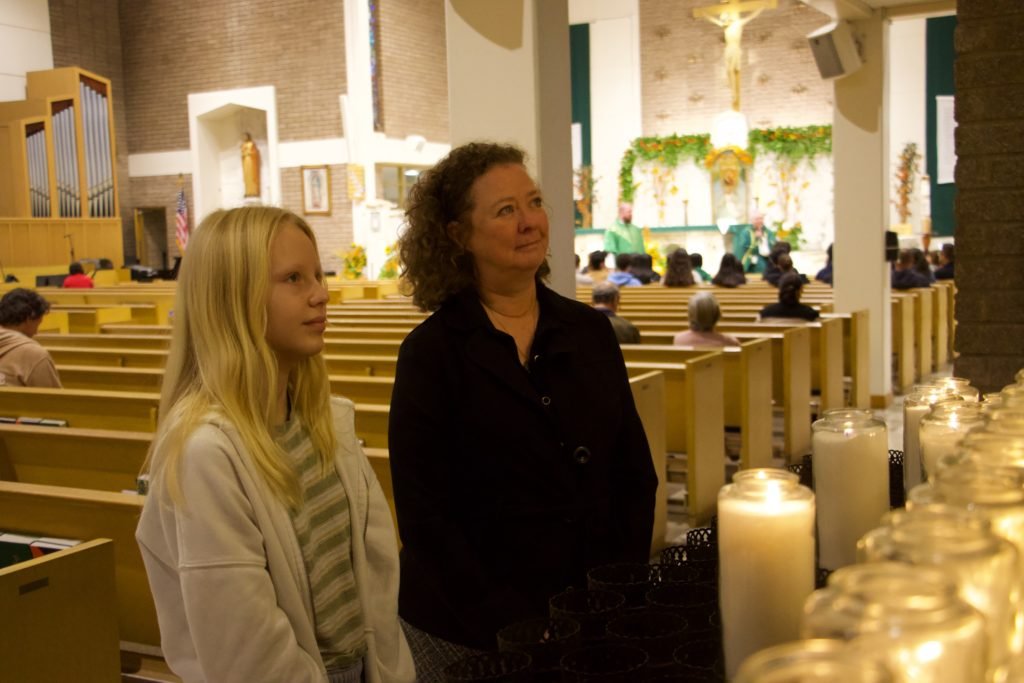 Laura Whisler, derecha, coordinadora religiosa en Our Mother of Good Counsel en Los Feliz, y Mercy Lavietes, izquierda, rezan durante la Misa de “Stand Up Sunday” en la parroquia el 16 de noviembre. (Kimmy Chacón)