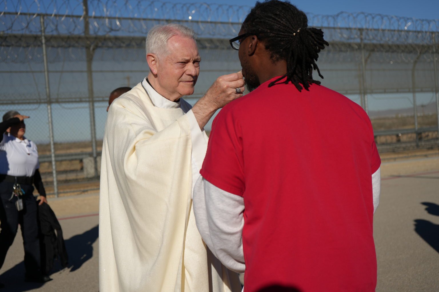 El obispo auxiliar de Los Ángeles, Matt Elshoff, distribuye la Comunión a un detenido durante la inusual Misa celebrada en el centro del ICE en Adelanto. (Conferencia Católica de California)