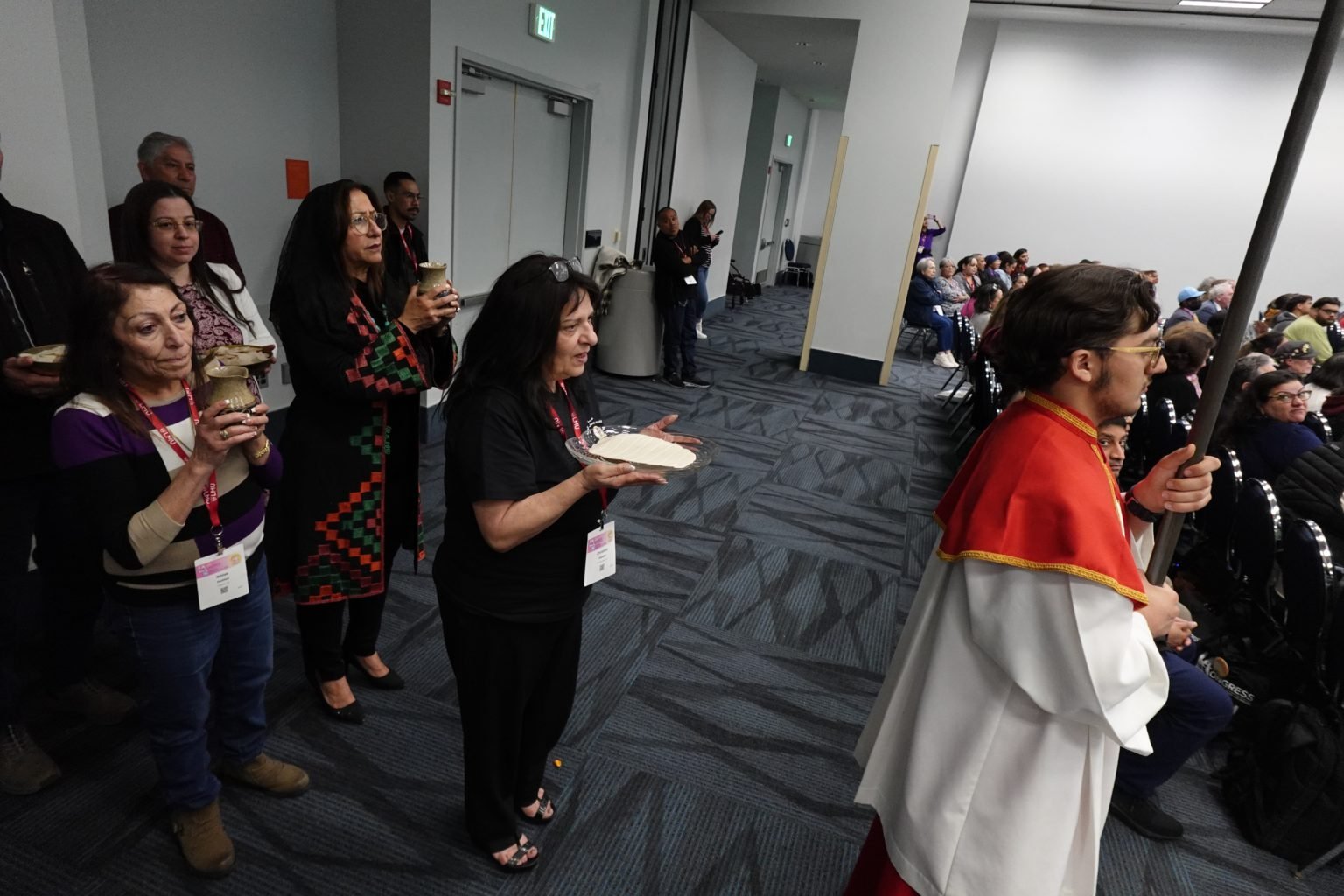 Feligreses llevan las ofrendas del pan y el vino durante la primera Misa en árabe en el RECongress, a la que asistieron cientos de personas el 21 de febrero. (Katie Trejo)