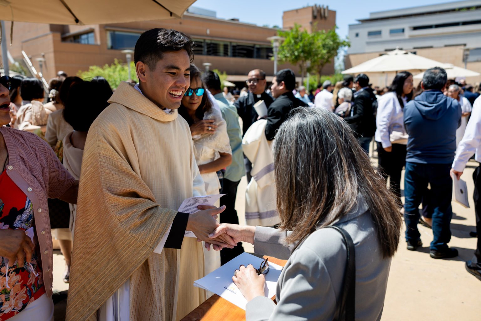 El padre Jerick Alenton saluda a una persona que se acercó a felicitarlo y le imparte su primera bendición tras la Misa de ordenación celebrada el 30 de mayo en la Catedral de Nuestra Señora de los Ángeles. (Joe Garcia III)