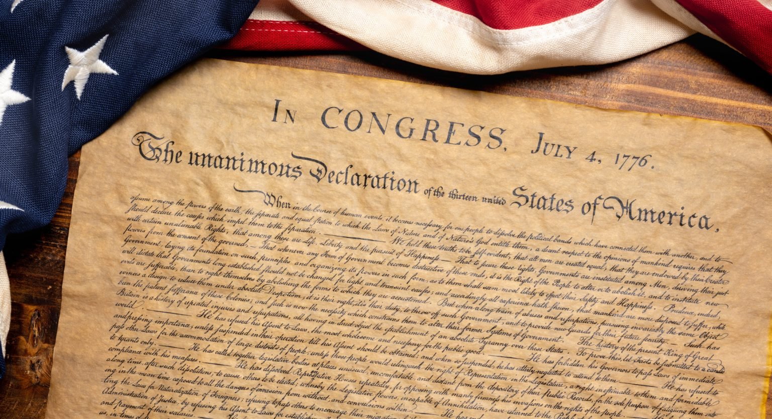Declaración de Independencia de Estados Unidos junto a una bandera estadounidense de estilo antiguo.