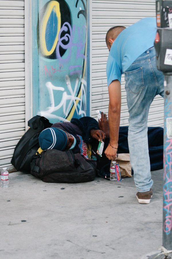 Los participantes se detuvieron para brindar ayuda concreta a las personas sin hogar en las aceras de Skid Row durante la procesión eucarística del 1 de agosto. (Katie Trejo)