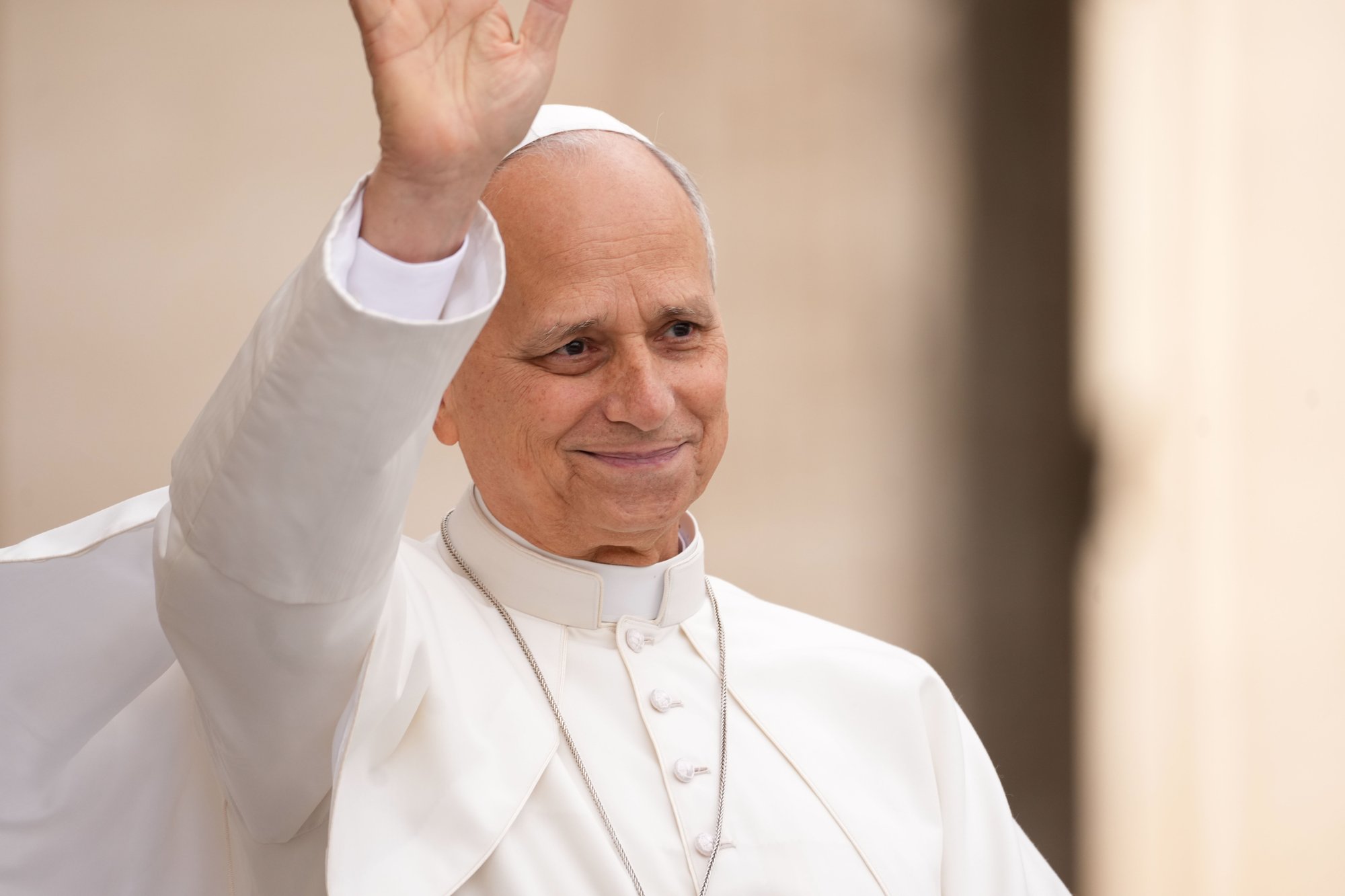 Pope Leo XIV smiles and waves from the popemobile