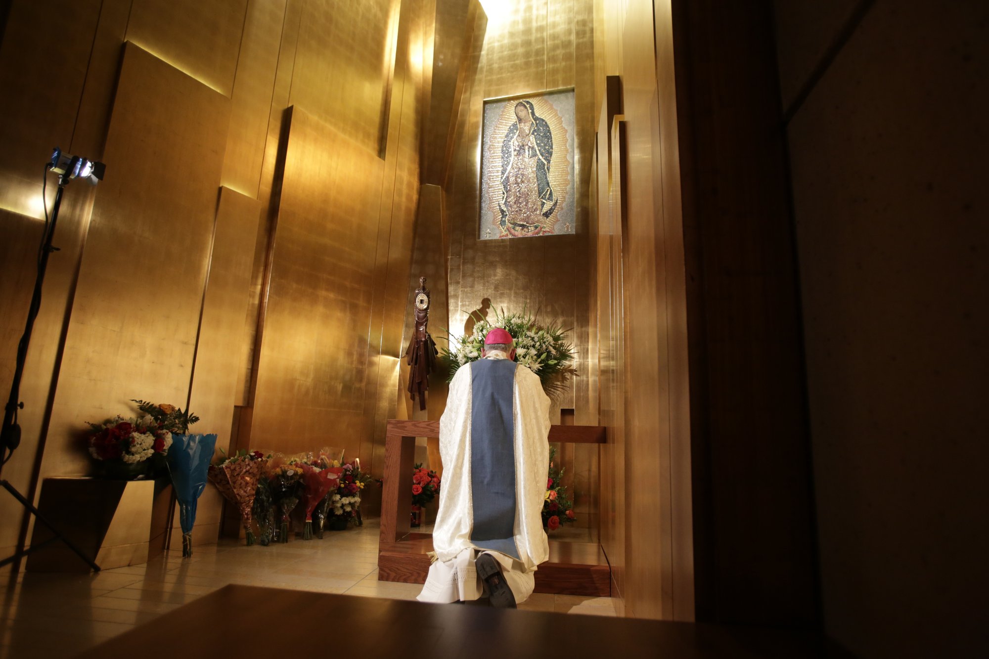 Archbishop Gomez prays before tilma fragment in LA Cathedral.