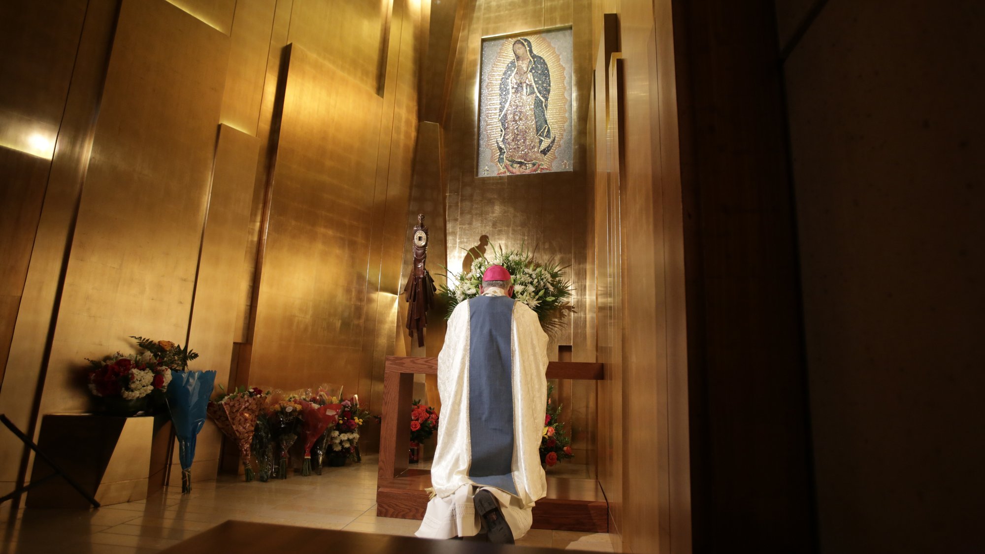 Archbishop Gomez prays before tilma fragment in LA Cathedral.