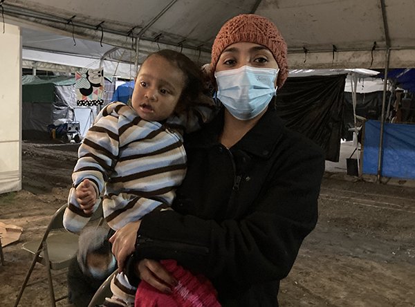 Adalia Reyes, una solicitante de asilo de El Salvador, posa con el hijo de un amigo fuera de una misa celebrada el 9 de enero de 2021, en un campamento de tiendas de campaña para migrantes a lo largo de la frontera entre Estados Unidos y México en Matamoros. (Foto: foto del SNC/David Agren)