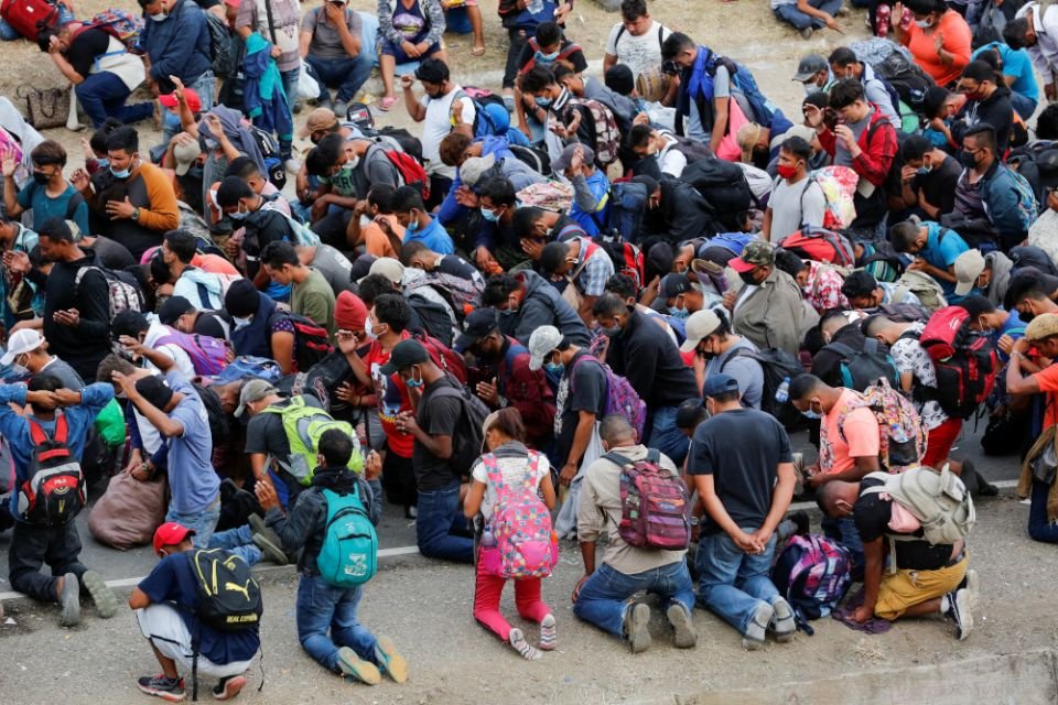 Una caravana de migrantes principalmente hondureños que se dirigen a los Estados Unidos se arrodilla en oración en Vado Hondo, Guatemala, el 17 de enero de 2021. Los católicos que trabajan con migrantes están dando la bienvenida a la postura del presidente estadounidense Joe Biden hacia Centroamérica, pero advierten que los factores de empuje están aumentando. (CNS/Reuters/Luis Echeverría)