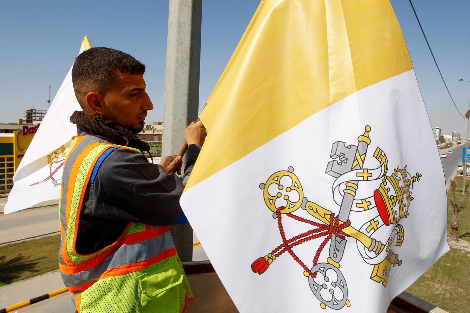 Un trabajador cuelga la bandera del Vaticano en un poste de servicios públicos en Najaf, Irak, el 27 de febrero. CNS/ALAA AL-MARJANI, REUTERS