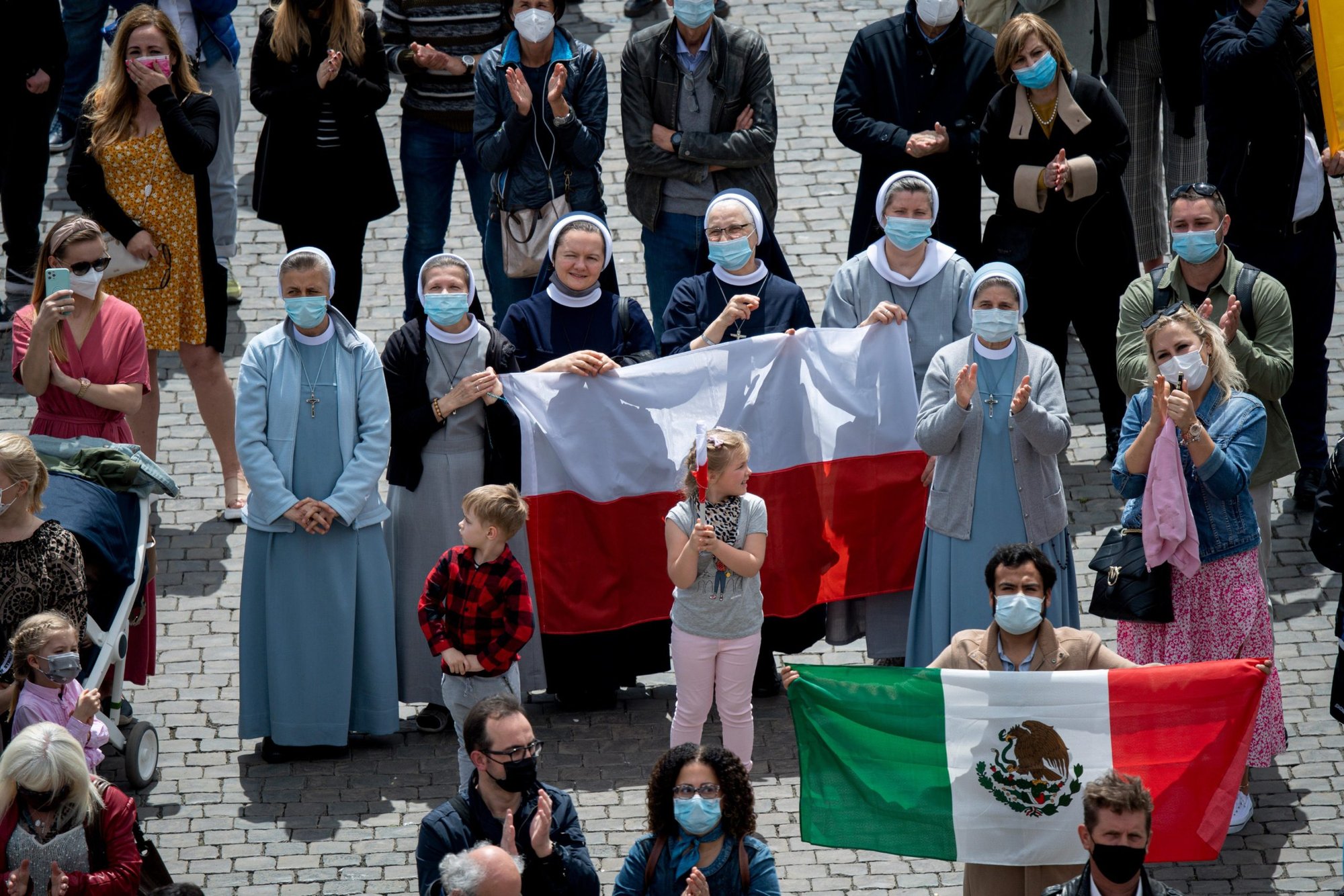 La gente sostiene las banderas nacionales de Polonia y México en la Plaza de San Pedro mientras asisten a la "Regina Coeli", dirigida por el Papa Francisco desde la ventana de su estudio con vistas a la Plaza de San Pedro en el Vaticano el 2 de mayo de 2021. (Foto CNS/Medios Vaticanos)