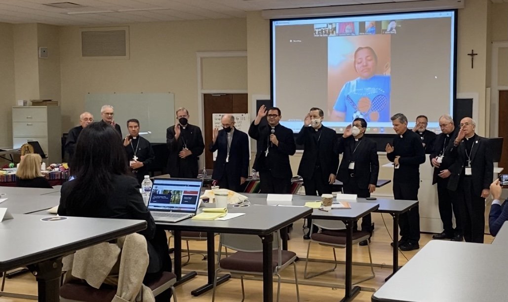 Obispos de Estados Unidos, Centroamérica y México, por medio de una cámara en el Seminario Mundelein en las afueras de Chicago el 2 de junio de 2021, bendicen a una mujer salvadoreña a través de Zoom después de que compartió su historia de inmigración con ellos. Junto con representantes del Vaticano y organizaciones católicas, los prelados participaron en una sesión de emergencia el 1 y 2 de junio para exponer la respuesta de la iglesia estadounidense a la inmigración, así como para buscar una mayor colaboración con los obispos de los países de donde provienen algunos migrantes.(Foto CNS/Rhina Guidos)