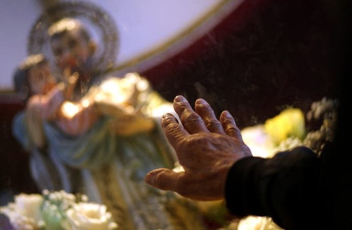 Un hombre toca el cristal delante de una estatua de San Cayetano el 7 de agosto en una iglesia de Buenos Aires, Argentina. Tradicionalmente, la gente celebra la fiesta del santo con una procesión y oraciones en las que se apela al patrón de los buscadores de empleo. Este año las celebraciones serán a través de internet, y se extenderán durante todo el mes debido a la pandemia de coronavirus COVID-19. (Foto: Marcos Brindicci/Reuters vía CNS.)