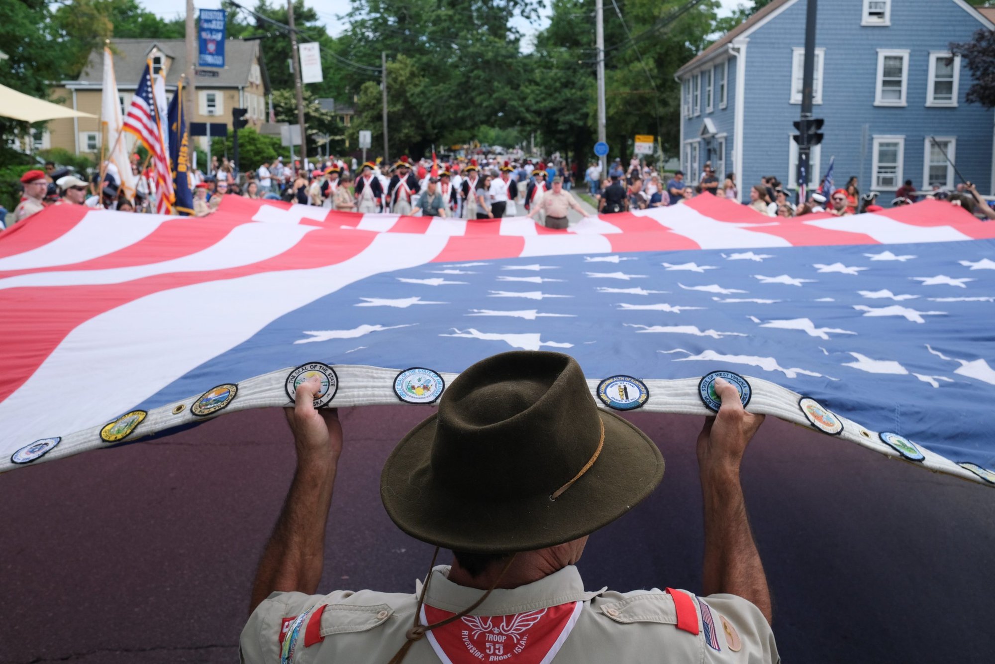 A Boy Scout leader in Bristol, R.I., helps stretch the American Flag to begin the 236th annual Military, Civic and Firemen's Parade July 5, 2021. (CNS photo/Quinn Glabicki, Reuters)