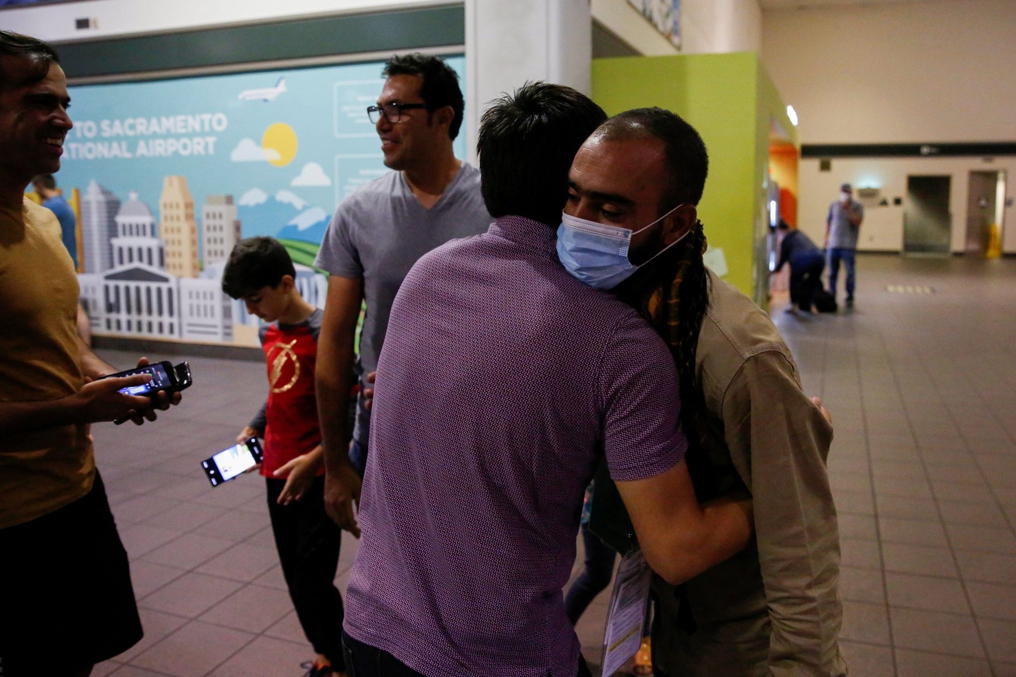 Sayed Abdul Wase Majidi abraza a su sobrino Sayed Mustafa Miri, de 38 años, después de que Majidi llega desde Fort Lee, Virginia, al Aeropuerto Internacional de Sacramento en Sacramento, California, el 5 de agosto de 2021. Sayed Abdul Wase Majidi es uno doscientos de intérpretes y traductores afganos traídos a Estados Unidos para ser reasentados, ya que miles más que ayudaron a las tropas estadounidenses siguen bajo amenaza en Afganistán mientras esperan ser evacuados. (Foto CNS/Brittany Hosea-Small, Reuters)