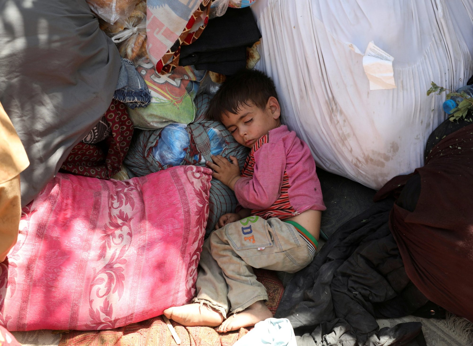 Un niño desplazado de las provincias del norte de Afganistán, que huyó con su familia debido a los combates entre los talibanes y las fuerzas de seguridad afganas, duerme en un parque público de Kabul el 10 de agosto de 2021. (Foto CNS/Reuters)