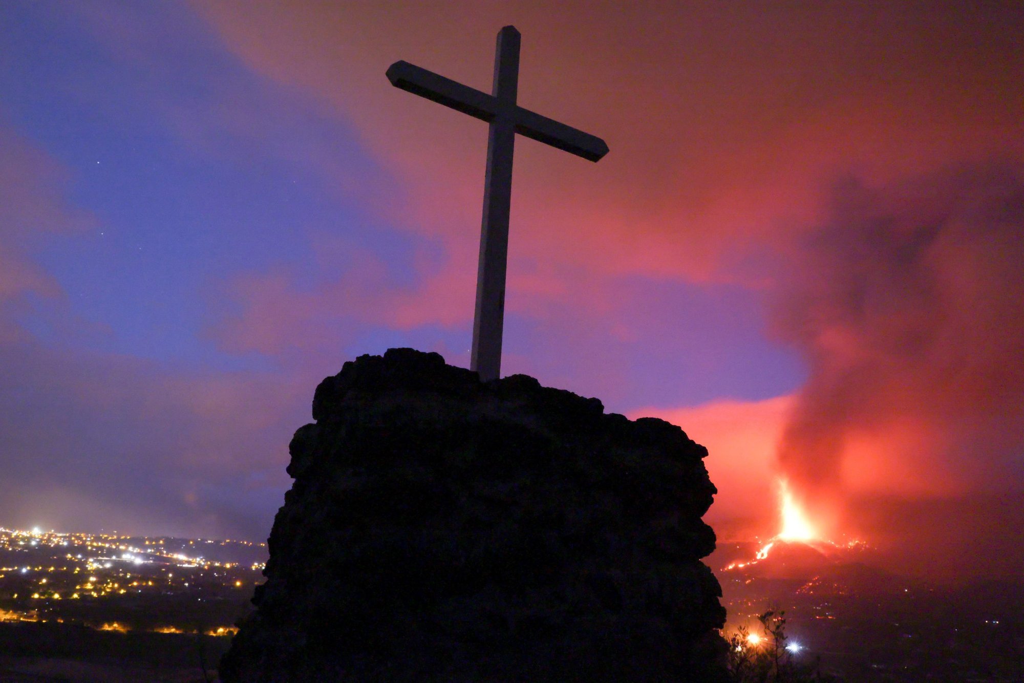 Una cruz aparece en esta foto mostrando la lava y el humo después de la erupción de un volcán en la isla española de La Palma el 21 de septiembre de 2021. Hasta el 22 de septiembre, la erupción había destruido casi 200 casas y forzó la evacuación de al menos 6,000 personas. (Foto CNS/Nacho Doce, Reuters)