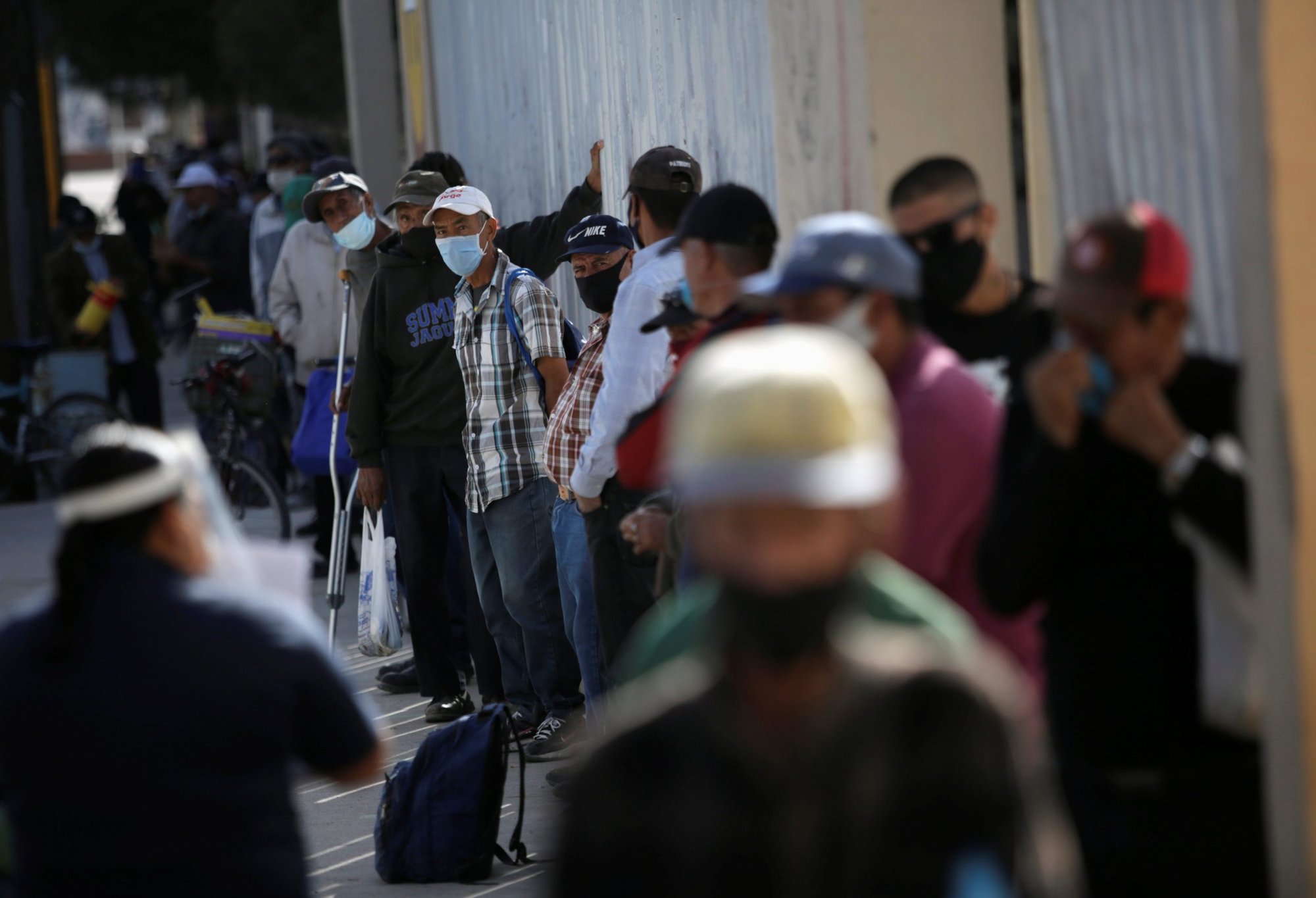 Un grupo de personas hacen fila para comer afuera de un comedor comunitario en Ciudad Juárez, México, el 15 de octubre de 2020, durante la pandemia de COVID-19. Las economías latinoamericanas se contrajeron un 7% en 2020, la peor de todas las regiones a nivel mundial, según el Fondo Monetario Internacional. (Foto CNS/José Luis González, Reuters)