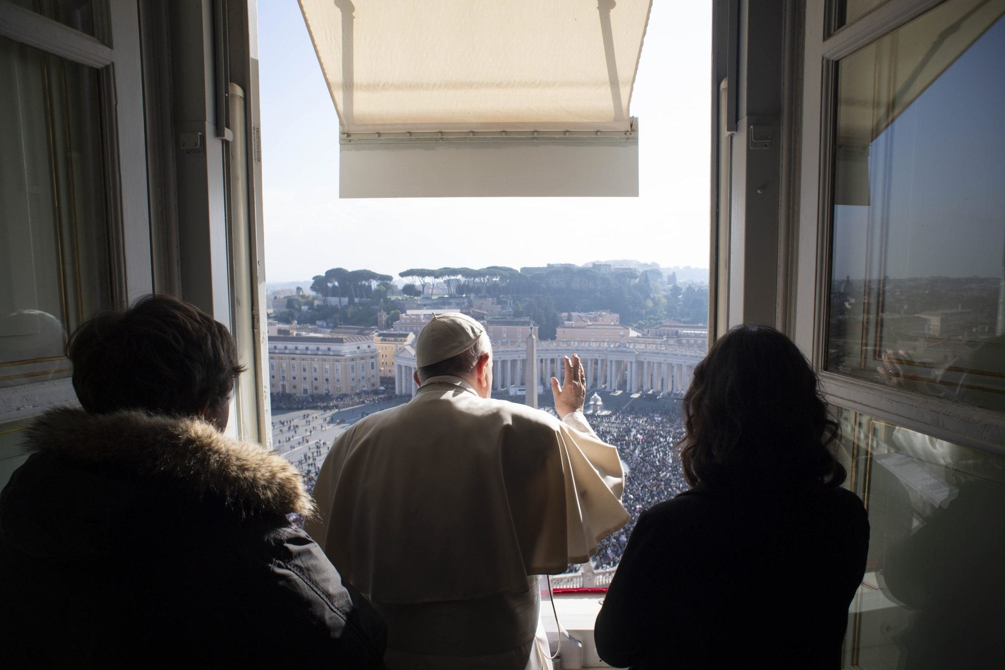 El papa Francisco, acompañado por dos jóvenes de la Diócesis de Roma, dirige el Ángelus desde la ventana de su estudio con vista a la Plaza de San Pedro en el Vaticano el 21 de noviembre de 2021. (Foto CNS/Vatican Media)