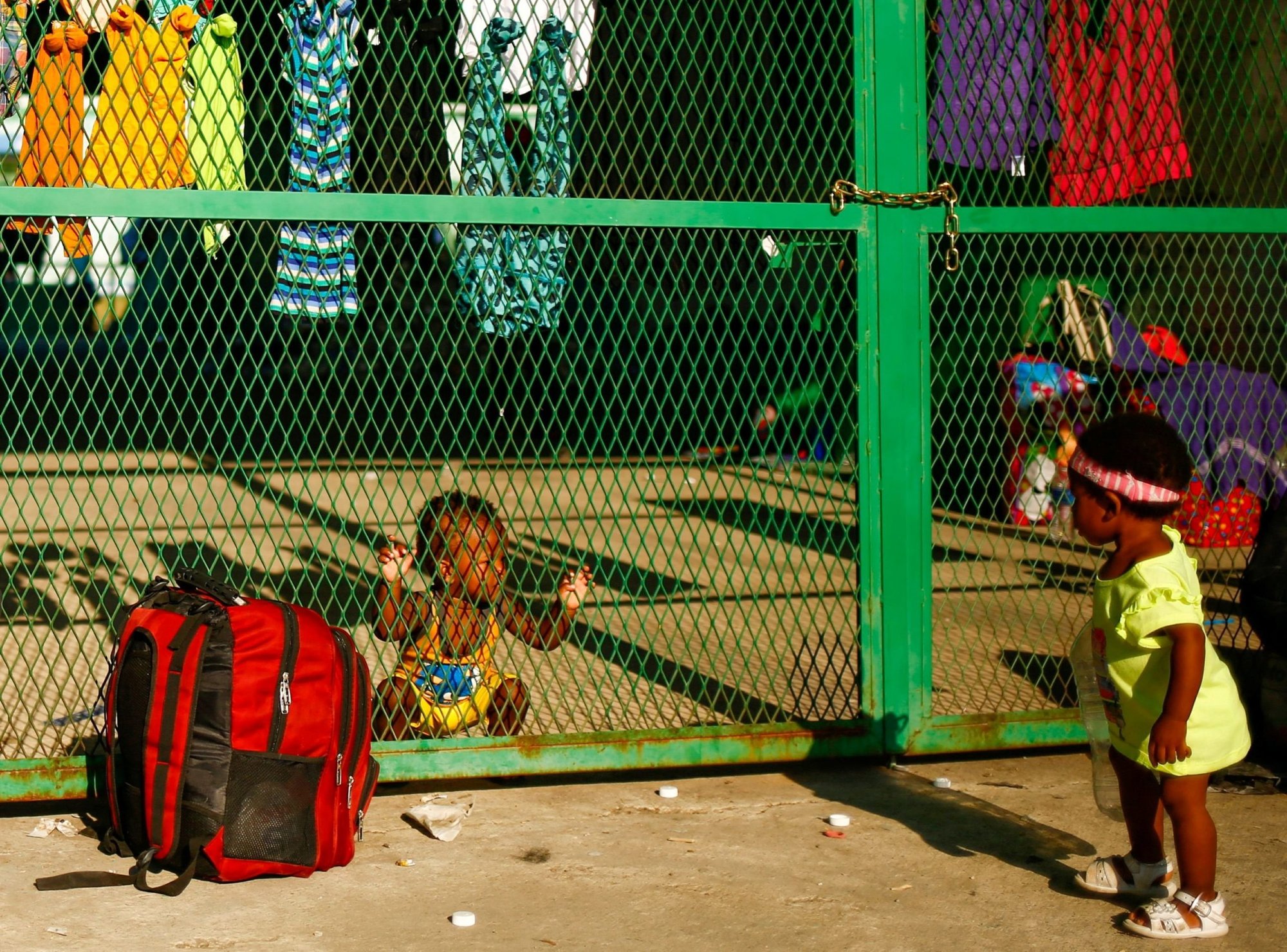 Niños en Tapachula, México, cerca de la frontera con Guatemala, se miran a través de un cerco mientras migrantes esperan recibir ayuda del gobierno mexicano el 2 de diciembre de 2021 para obtener visas humanitarias para pasar por territorio mexicano. (Foto CNS/José Luis González, Reuters)