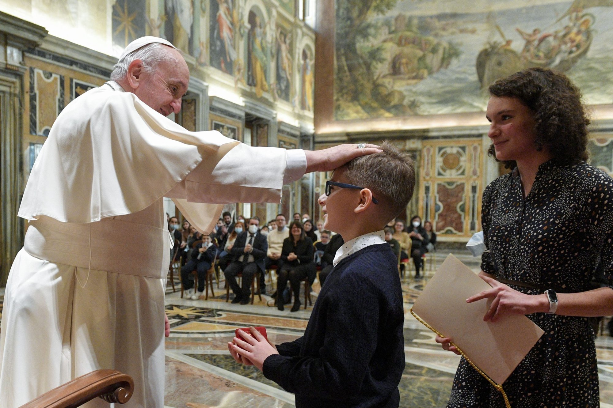 El Papa Francisco toca la cabeza de un niño durante un encuentro con niños de la Acción Católica de Italia en el Vaticano el 18 de diciembre de 2021. (Foto CNS /Vatican Media)