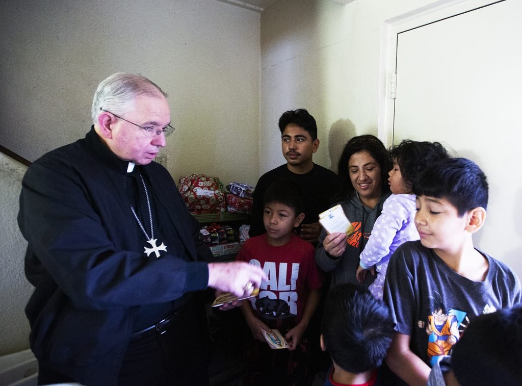 Monseñor Gómez entrega los regalos a uno de los beneficiarios de Adopta una Familia en 2019. (Víctor Alemán)