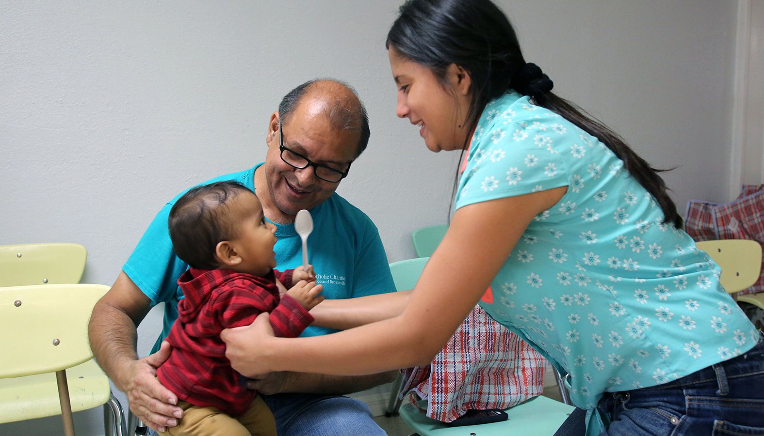 Una voluntaria de un Centro de Respiro Humanitario de Caridades Católicas entrega a un niño refugiado centroamericano a su madre para que tome un autobús para ir a quedarse con una familia estadounidense. (Vic Hunterlang/Shutterstock)