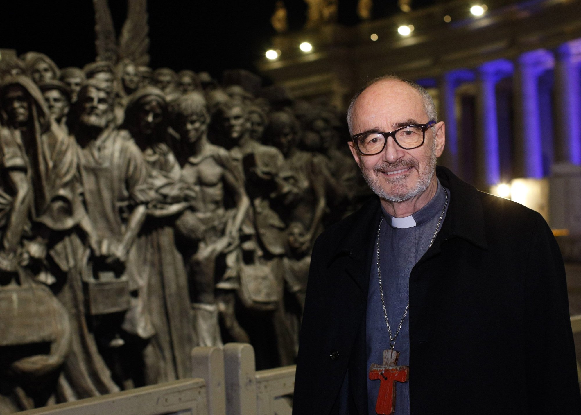 El cardenal Michael Czerny, subsecretario para los migrantes y los refugiados en el Dicasterio Vaticano para la Promoción del Desarrollo Humano Integral, posa para una foto en la estatua de los "Ángeles desprevenidos" en la Plaza de San Pedro en el Vaticano el 15 de diciembre de 2020. (Foto CNS /Paul Haring)