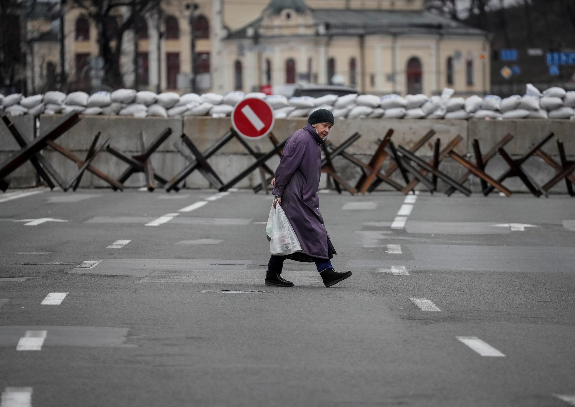 Una mujer cruza la calle mientras se ven construcciones antitanques en Kyiv, Ucrania, el 7 de marzo de 2022. (Foto CNS/Gleb Garanich, Reuters)
