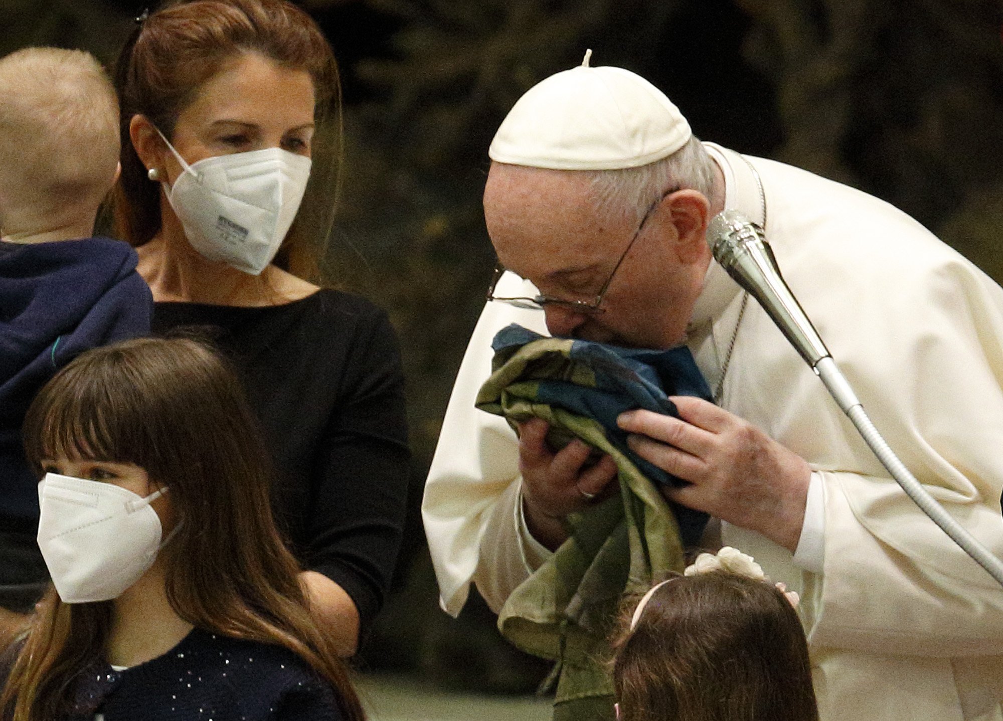 El Papa Francisco besa una bandera nacional ucraniana de Bucha mientras se reúne con refugiados ucranianos durante su audiencia general en el aula Pablo VI del Vaticano el 6 de abril de 2022. (Foto CNS /Paul Haring)