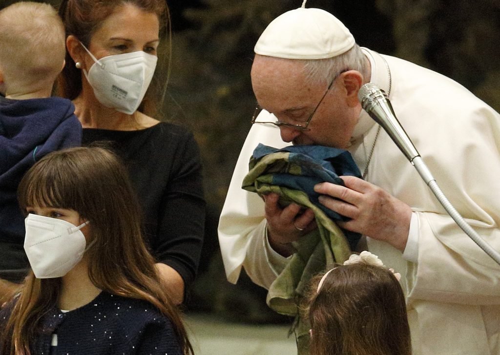 El Papa Francisco besa una bandera nacional ucraniana de Bucha mientras se reúne con refugiados ucranianos durante su audiencia general en el aula Pablo VI del Vaticano el 6 de abril de 2022. (Foto CNS/Paul Haring)