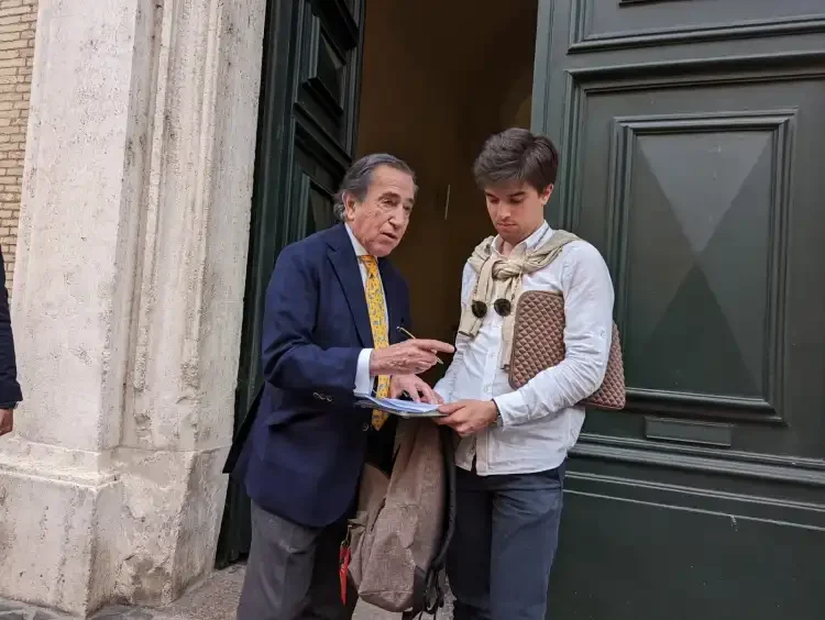 El psiquiatra español Enrique Rojas, director del Instituto Español de Psiquiatría, autografía un libro a un joven estudiante en Roma, frente a la Universidad Pontificia de la Santa Cruz. (Foto Inés San Martín/Crux)