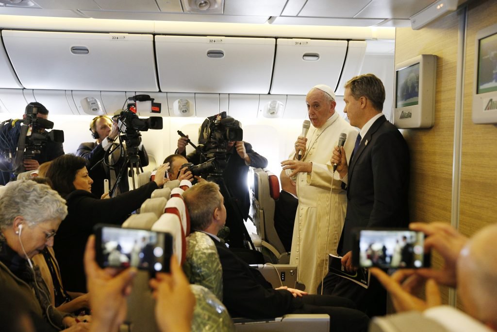 El Papa Francisco saluda a los periodistas a bordo de un vuelo de Roma a Santiago de Chile, en 2018. (Foto CNS/Paul Haring)
