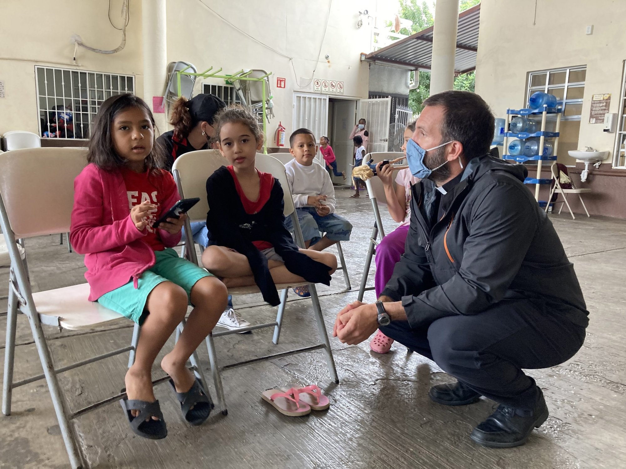 El padre jesuita Brian Strassburger conversa con jóvenes migrantes el 24 de mayo de 2022 en el albergue diocesano para migrantes en Reynosa, México. El sacerdote estadounidense y un colega jesuita trabajan con inmigrantes que no pueden solicitar asilo en los Estados Unidos. (Foto CNS/David Agren)