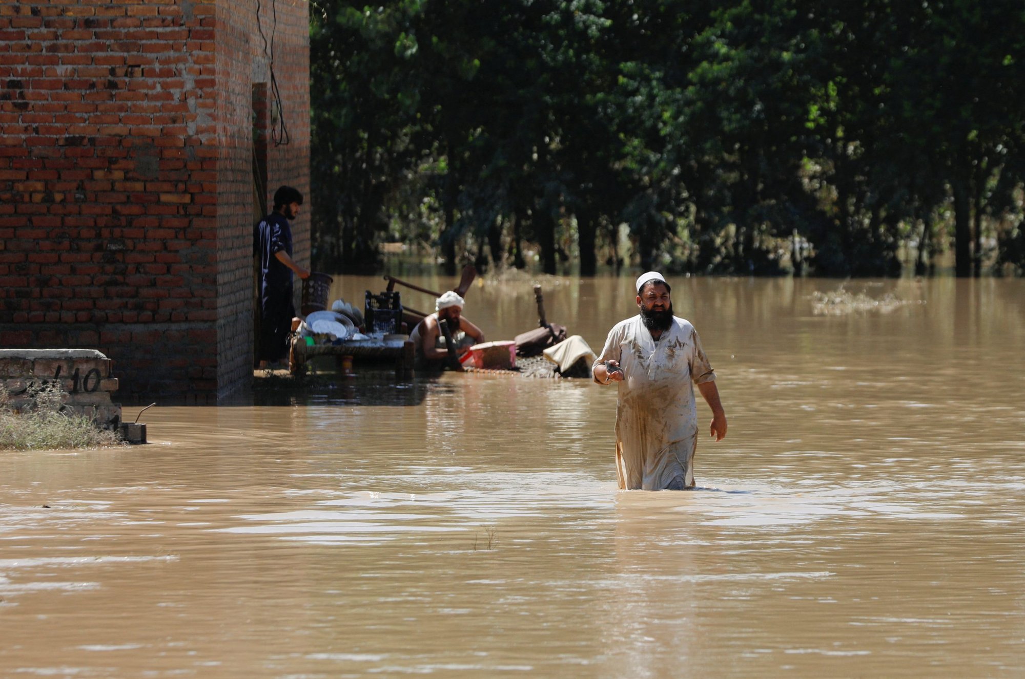 Un hombre vadea las aguas de la inundación, tratando de salvar sus pertenencias, luego de las fuertes lluvias durante la temporada del monzón en Charsadda, Pakistán, el 28 de agosto de 2022. (CNS photo/Fayaz Aziz, Reuters)