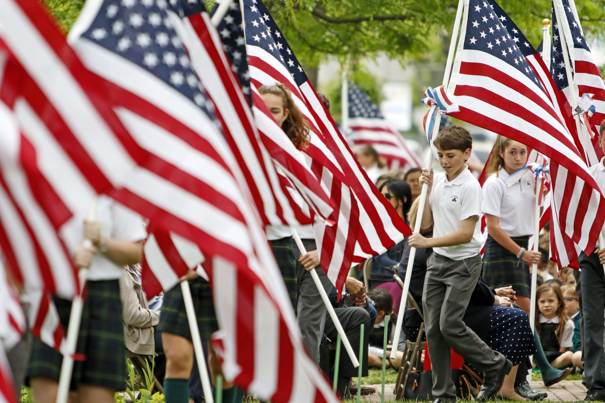 Los estudiantes de la escuela de San Patricio en Bay Shore, Nueva York, crean un campo de honor para los veteranos vivos y fallecidos de las fuerzas armadas de Estados Unidos mientras colocan 100 banderas de Estados Unidos en el jardín delantero de la escuela el 24 de mayo de 2017. Los obispos de Estados Unidos esperan comprometer mejor a los jóvenes con la Iglesia a través del Instituto sobre el Catecismo que se lanzará del 10 al 12 de noviembre de 2022, justo antes de su asamblea general de otoño en Baltimore. (CNS photo/Gregory A. Shemitz)