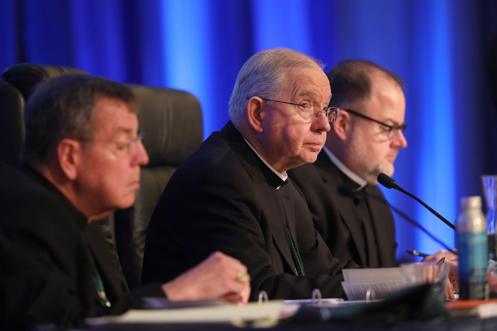 El arzobispo de Detroit, Allen H. Vigneron, vicepresidente saliente de la Conferencia Episcopal de Estados Unidos, y el arzobispo de Los Ángeles, José H. Gómez, presidente saliente, asisten a una sesión de la asamblea general de otoño de la conferencia episcopal el 15 de noviembre de 2022 en Baltimore. También aparece el padre Michael Fuller, secretario general. (CNS /Bob Roller)