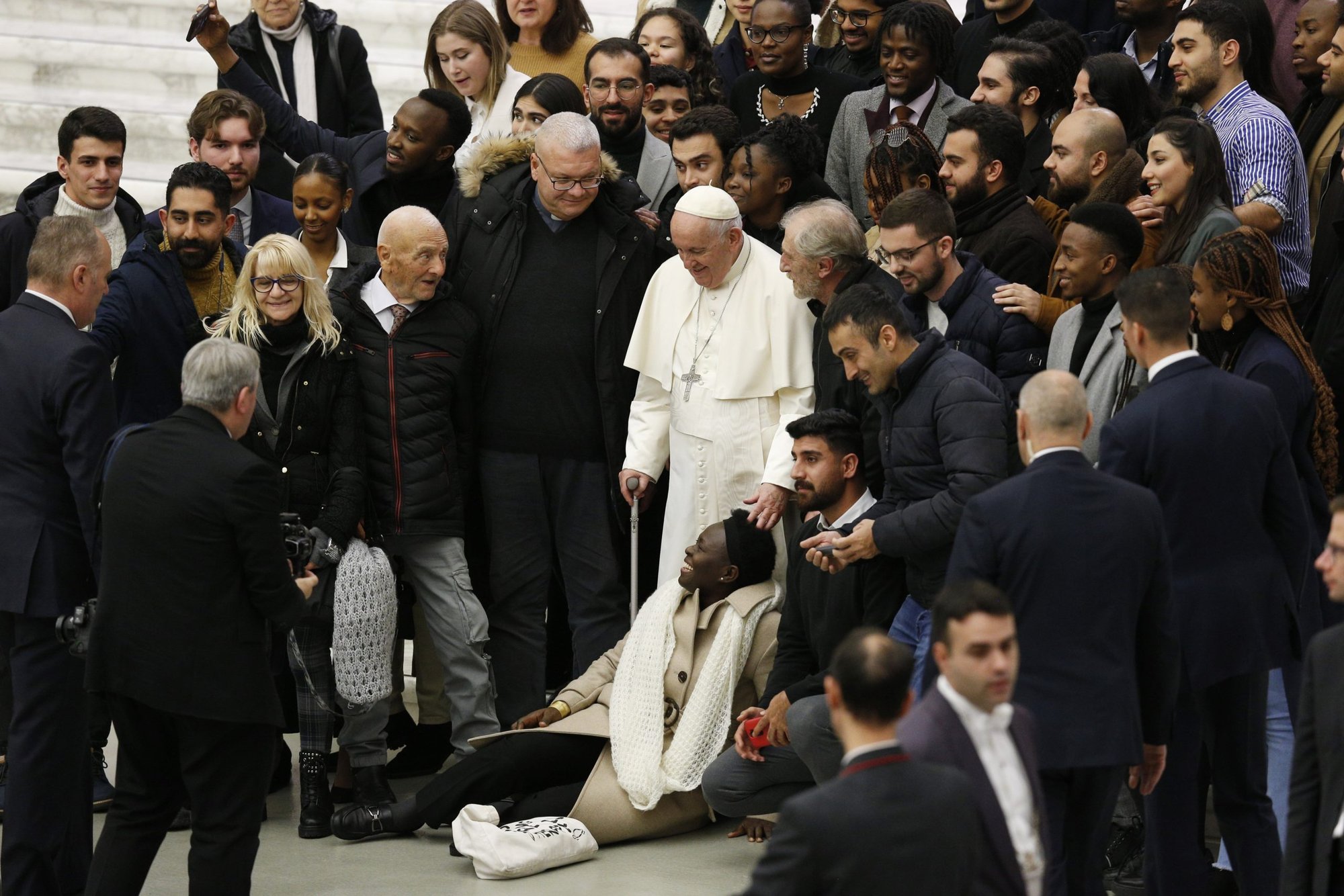 El papa Francisco toca la cabeza de una mujer mientras posa con un grupo de personas durante su audiencia general en el aula Pablo VI del Vaticano el 21 de diciembre de 2022. (Foto CNS/Paul Haring)